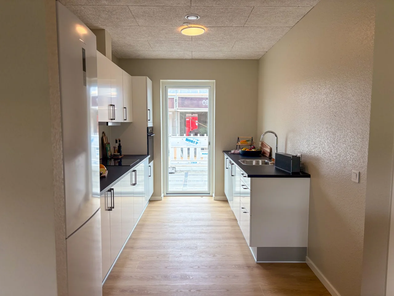 Køkken med hvide fronter og mørk bordplade i prøveboligen